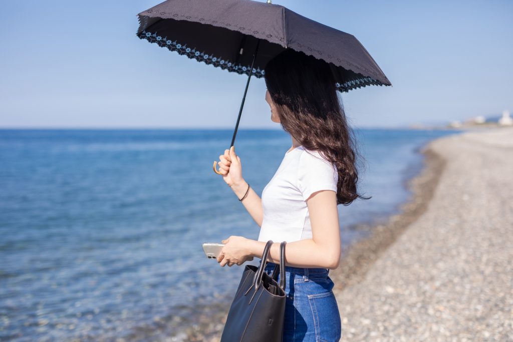 海辺で日傘を差す女性