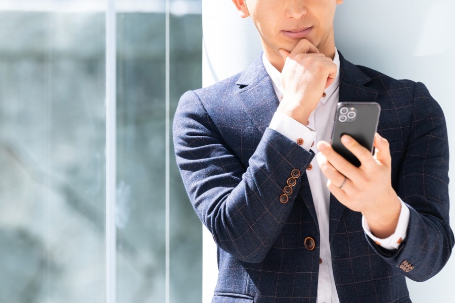 スマートフォンの画面を見て驚く男性